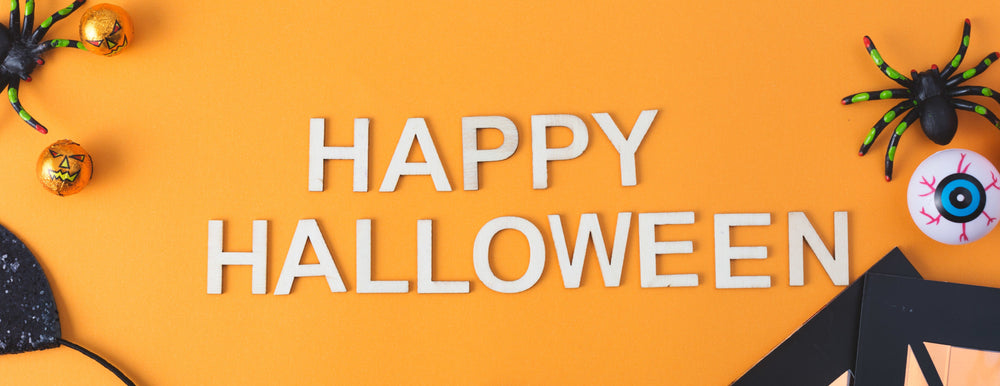 Happy Halloween text on an orange background with Halloween decorations.